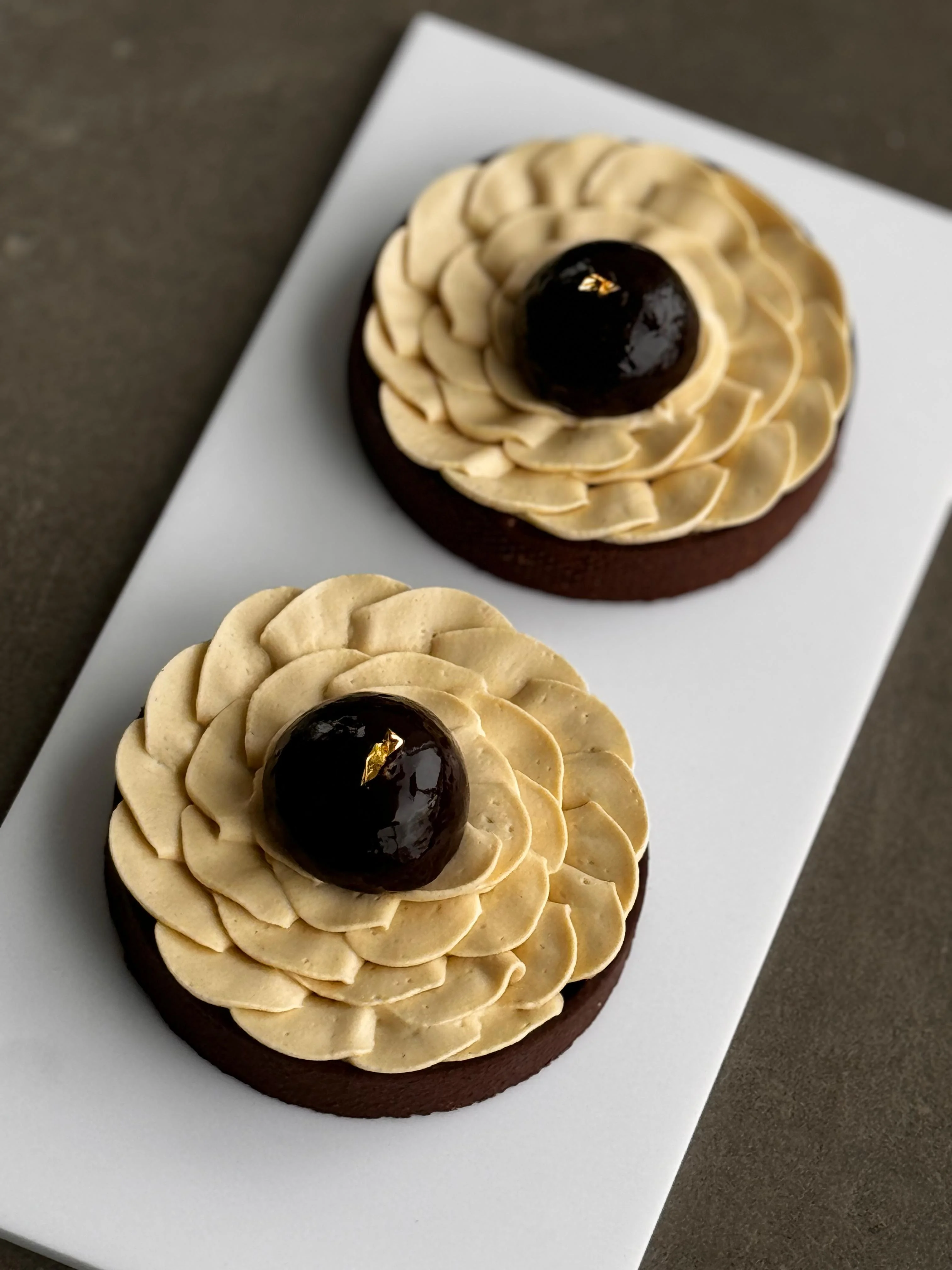 Chrysanthème tart — dark chocolate sablé with layered chestnut cream rosette and dark chocolate mirror dome, gold leaf
